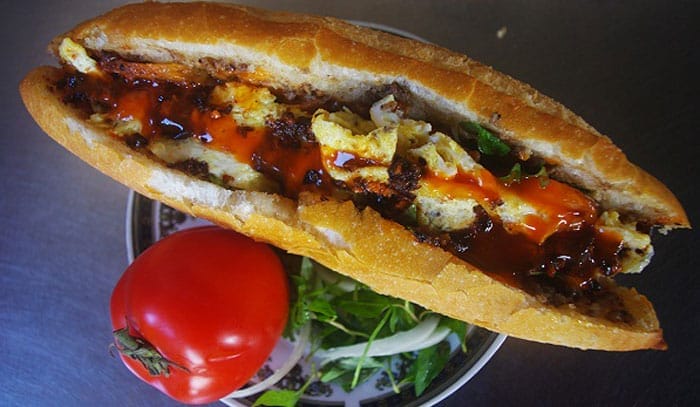 Nếu bạn đang tìm một nơi để thưởng thức bánh mì Hội An đúng chuẩn – nhanh, ngon và không phải xếp hàng dài chờ đợi, thì bánh mì Bích chính là điểm dừng chân lý tưởng. Mỗi ổ bánh mì ở đây là sự kết hợp hoàn hảo giữa lớp vỏ giòn rụm và phần nhân đậm đà, đặc biệt là pate thơm lừng – bí quyết riêng của quán, béo nhưng không ngấy, ăn hoài không chán. Hương vị đặc trưng ấy khiến không ít du khách phải “nhớ mãi không quên”. Đừng bỏ lỡ cơ hội ghé quán và cảm nhận một trong những hương vị bánh mì đáng thử nhất tại Hội An!