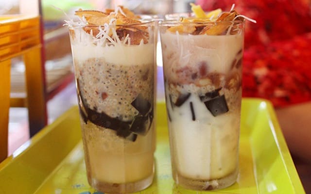Dù chè thập cẩm là món quen thuộc ở khắp nơi, nhưng khi ghé quán chè cô Sáu nằm giản dị bên vỉa hè đường Nguyễn Tất Thành, bạn sẽ cảm nhận được một điều rất khác — cảm giác như được trở về tuổi thơ, ngồi bên những bộ bàn ghế nhựa học sinh, vừa ăn chè vừa nghe tiếng rao, tiếng xe cộ rì rào như một bản nhạc ký ức.