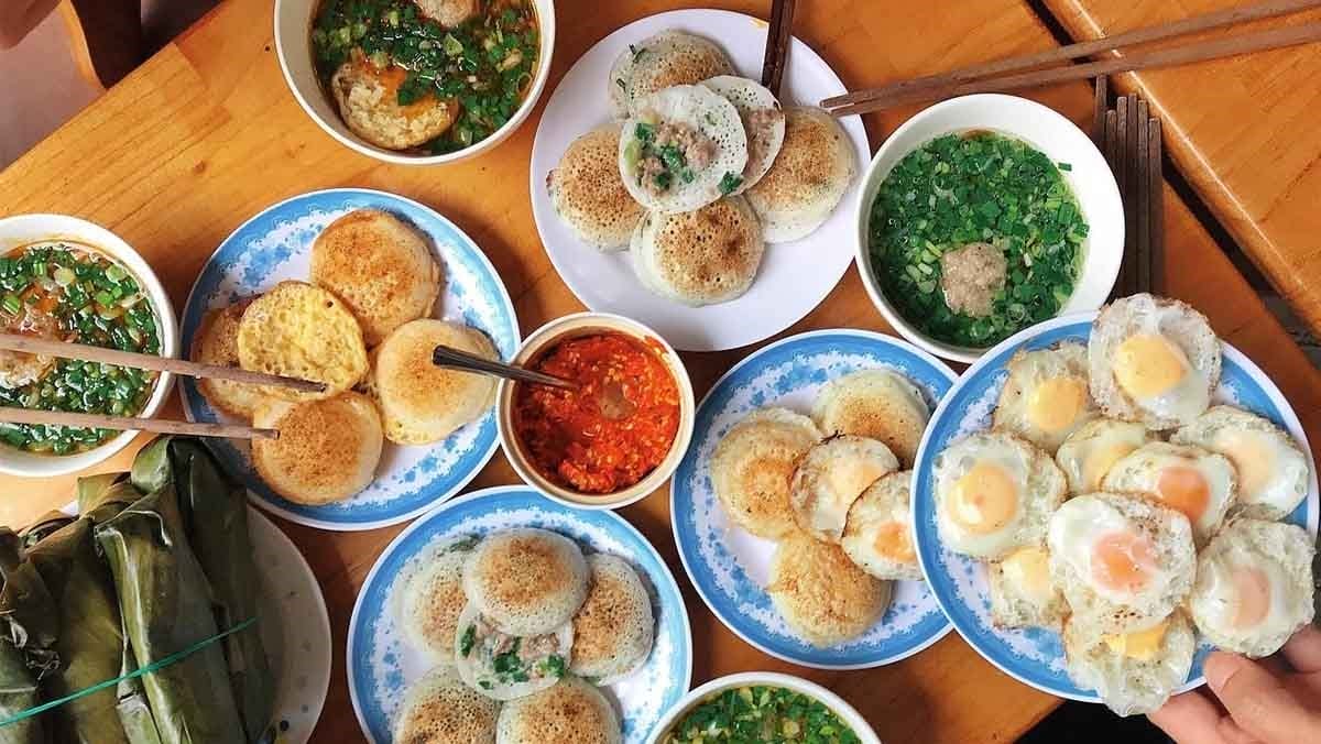 Bánh căn Hội An được làm từ bột gạo pha loãng, đổ vào khuôn đất nung nóng hổi có nhiều lỗ tròn nhỏ. Khi bánh vừa se mặt, người bán nhanh tay cho thêm nhân như tôm tươi, thịt heo băm, trứng cút… rồi đậy nắp lại, để chiếc bánh “chín tới” một cách hoàn hảo. Bánh căn giòn rụm bên ngoài, mềm dai bên trong, thơm ngậy mà không hề ngán – cắn một miếng là nhớ mãi không quên.