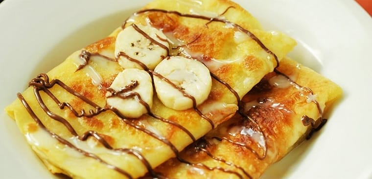 Crepe chuối là một trong những món ngọt ăn vặt đặc trưng mà bạn nhất định phải thử khi đến Hội An. Không cần đi đâu xa, chỉ cần dạo một vòng chợ đêm, bạn sẽ dễ dàng bắt gặp hình ảnh các quầy hàng rộn ràng đổ bánh, tỏa hương thơm quyến rũ. Món bánh hấp dẫn thực khách bởi lớp vỏ mỏng giòn, nhân chuối chín ngọt lịm hòa quyện cùng vị béo thơm của sữa và bơ, tạo nên hương vị khó quên giữa lòng phố cổ.