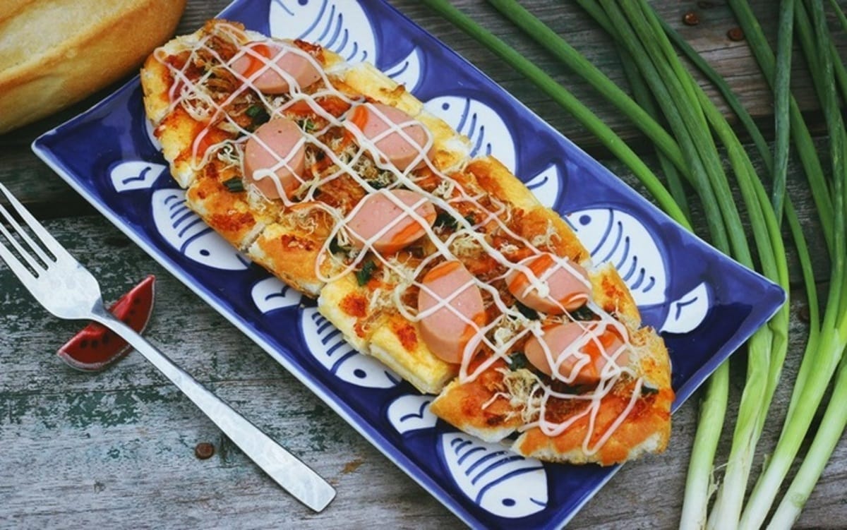 Nếu bạn là tín đồ mê ăn vặt, nhất định không thể bỏ lỡ món bánh mì nướng muối ớt tại quán NiNa – một “tọa độ” cực hot ở Hội An. Tại đây, chiếc bánh mì giòn tan, phủ đầy chà bông thơm lừng, đậm vị muối ớt cay nồng sẽ khiến bạn “đổ gục” ngay từ miếng đầu tiên. Gia vị được nêm nếm vừa vặn, thấm đều từng lớp bánh, tạo nên một hương vị ngon khó cưỡng khiến ai ăn rồi cũng muốn quay lại.