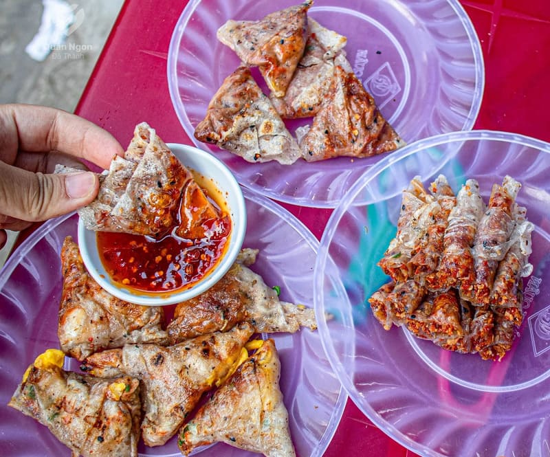 Ẩm thực Hội An phong phú là thế, nhưng có một món ăn vặt giản dị lại khiến bao du khách say mê không thôi - bánh kẹp Hội An. Mỗi chiếc bánh kẹp được chế biến tỉ mỉ ngay tại chỗ, lớp bánh tráng dừa vàng ruộm quyện với pate béo ngậy, điểm xuyến vị cay nồng của tương ớt. Một cắn thôi là đủ đánh thức mọi giác quan: vị mặn đậm đà của patê, vị cay tê đầu lưỡi, cùng chút ngọt béo từ bánh tráng dừa… Hòa quyện lại thành một "bữa tiệc" vị giác khó quên.