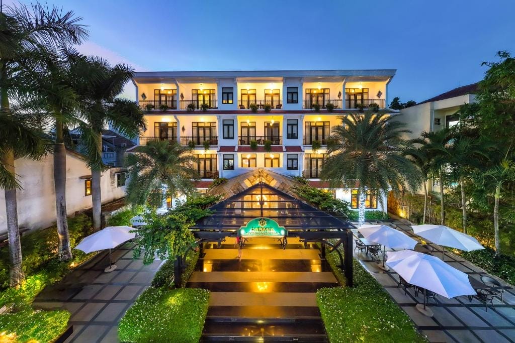 Hadana Boutique Resort Hội An là một điểm dừng chân tuyệt vời kết hợp giữa tinh hoa văn hóa phố cổ và sự tiện nghi hiện đại. Chỉ cách trung tâm phố cổ Hội An khoảng 700 m, khu nghỉ dưỡng mang phong cách boutique này đậm chất Á Âu với thiết kế trang nhã, sử dụng tông màu trung tính kết hợp các chất liệu gỗ cùng kết cấu tinh tế để tạo nên không gian ấm cúng nhưng không kém phần sang trọng. Trải dài trên diện tích rộng với 95 phòng cùng các suite đa dạng – từ những phòng Deluxe đến các căn Family kết nối, Executive, Suite riêng biệt hay phòng Senior Deluxe, mỗi căn đều có ban công riêng, nơi du khách có thể ngắm nhìn vườn cây xanh mướt, hồ bơi lấp lánh, thậm chí cả cánh đồng lúa yên bình phía xa